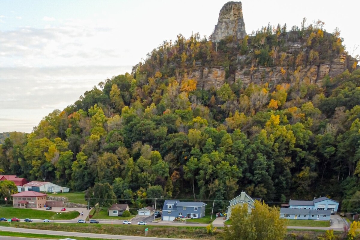 Sugar Loaf bluff above Winona, Minnesota, in autumn color, with houses and the highway below