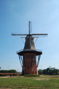 The brick Moinho Povos Unidos windmill in Holambra, its lattice sails spread against a clear blue sky above open fields.