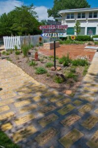 A brick pathway made of engraved paver bricks leading toward signs for Dorothy's House, a gift shop and Land of Oz in Liberal, Kansas.