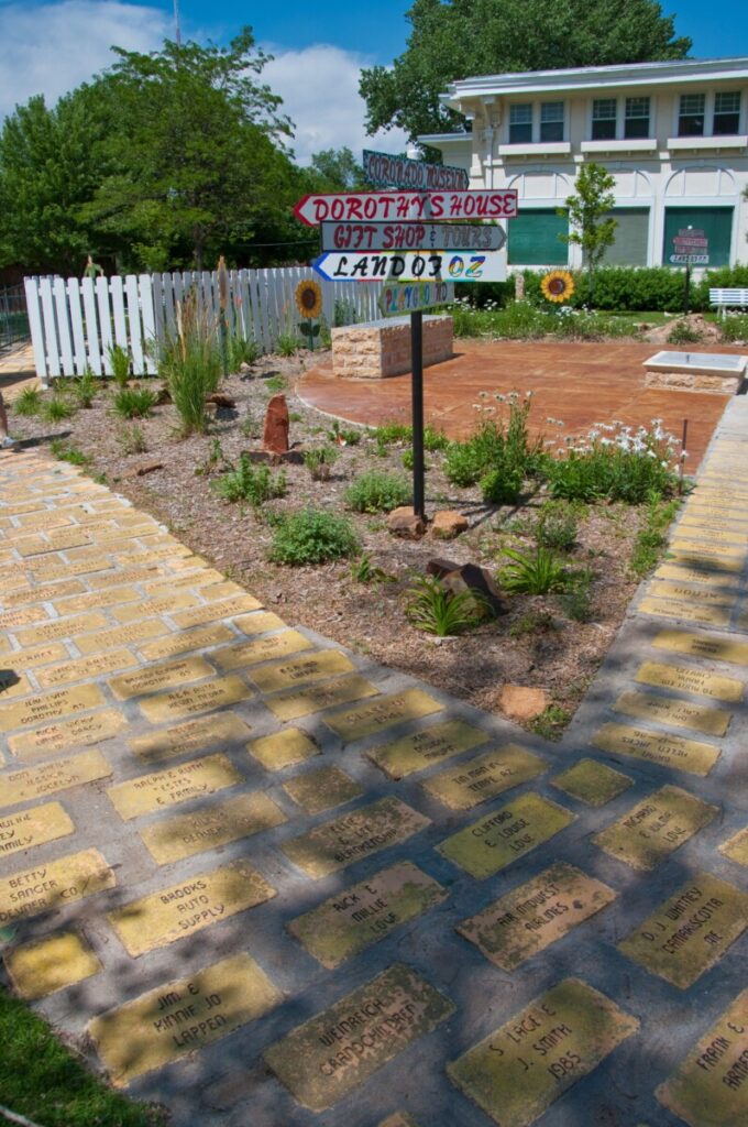 A brick pathway made of engraved paver bricks leading toward signs for Dorothy's House, a gift shop and Land of Oz in Liberal, Kansas.