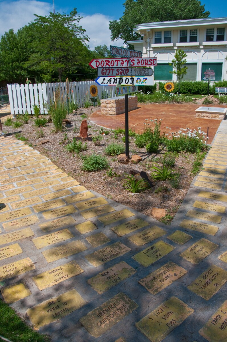 A brick pathway made of engraved paver bricks leading toward signs for Dorothy's House, a gift shop and Land of Oz in Liberal, Kansas.