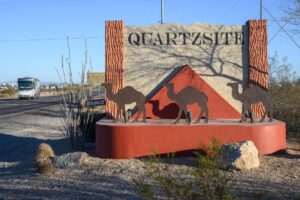 Located south of the town on Highway 95 is a sign announcing the town of Quartzsite, Arizona USA. The sign features a camel motif, alluding to the historical ex