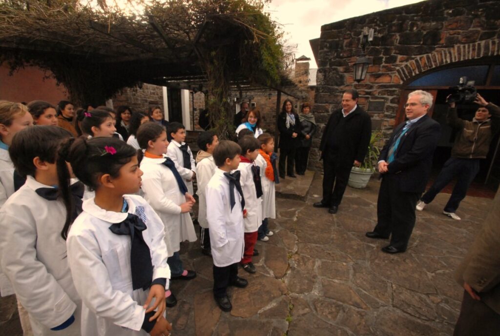 Uniformed schoolchildren from Valle Edén greet visiting officials in the stone courtyard of the Museo Carlos Gardel.