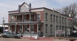 The two storey brick Hotel Wilber, built in 1895, with stacked porches, an American flag and a sign reading Hotel Wilber Bed and Breakfast Inn.