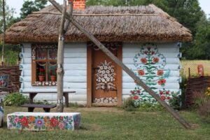 A Zalipie cottage with its walls, window frames and fence covered in brightly painted flowers, in the traditional Zalipie style.